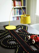 Gelbe Stehlampe und Spielzeugauto mit Spielteppich