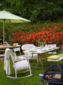 An afternoon barbeque in a garden with a red flower bed in the background