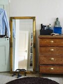 Full length mirror with a good frame next to an antique wooden chest of drawers