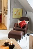 Leather chair with pillows and matching foot stool under a pitched roof