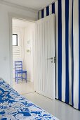 Zimmer mit blau weiss gestreiftem Vorhang und offener Zimmertür mit Blick in Vorraum