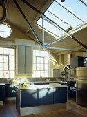 Offene Küche mit blauen Schrankfronten im Loft mit Glasoberlicht