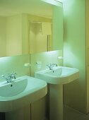 Zwei freistehende Waschbecken mit vollflächigem Wandspiegel und indirekter Beleuchtung
