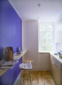 Moderne Küche mit Thekenablage und Barhocker vor blauer Wand