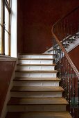 A stairway with a wooden banister and red-brown sponge-painted walls