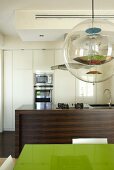 Designer pendant light above a table and open floor plan wooden kitchen unit