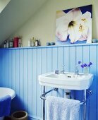 Blaues holzvertäfeltes Bad mit Waschbecken und Handtuchhalter