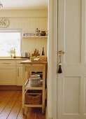 Blick in eine cremefarbene Küche mit beweglichem Arbeitstisch