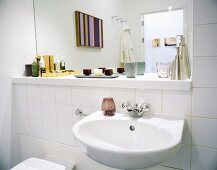 A wash basin and a mirror against a white tiled wall