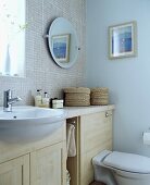 Waschtisch mit Unterschrank aus hellem Holz und Spiegel vor Mosaikfliesen