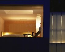 Blick durch Fenster in beleuchtetes Schlafzimmer