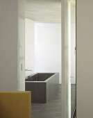 A view into a bathroom with a grey, cubic bathtub