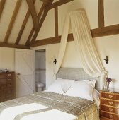 A double bed with a canopy in an attic bedroom in a country house