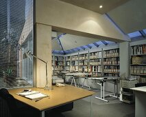 An architects office with an illuminated desk and a drawing table in front of a built in shelf