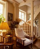 Edwardian Sessel mit weissen Polstern und gelber Lampenschirm neben Treppenaufgang in französischem Landhaus