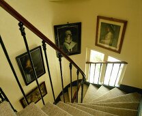 Viktorianische Portraits hinter zierlichem, antikem Geländer in mit Teppich belegtem, gewendeltem Treppenaufgang