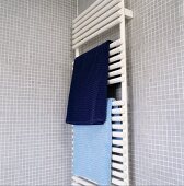 Blaue Handtücher auf weißem Stangenheizkörper in Bad mit hellgrauen Mosaikfliesen