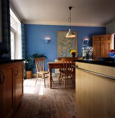 Moderne Küche mit rustikalem Essplatz vor blauer Wand mit brennenden Leuchten