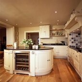 Kücheninsel mit integriertem Weinkühler in einer cremefarbenen Küche mit Holzboden