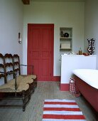 Rote Tür in und antike Stühle in einem Bad mit rot-weiß gestreiftem Teppich