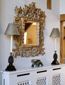 Quadratischer Spiegel mit geschnitztem Holzrahmen und zwei Lampen auf Heizkörperabdeckung
