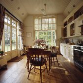 Gedrechselte Stühle mit Tisch aus Kiefernholz in hoher, weisser Landhausküche mit viel Fensterfläche
