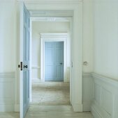 Pastellblaue Türen und niedrige Wandverkleidung zwischen Räumen mit Dielenboden und Natursteinplatten in Haus aus der georgianischen Zeit