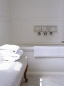 Ein Stapel weiße Handtücher sind auf einer gepolsterten Sitzbank, die in einem traditionellen Bad steht, gestapelt worden