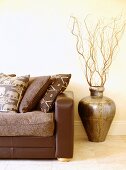 Ein braunes Leder-Sofa mit Kissen steht neben einer marokkanischen Vase