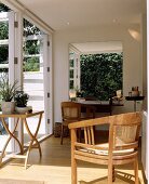 Holz-Sessel und Holztische sind auf dem Parkettboden der modernen und weißen Wohnzimmererweiterung platziert worden