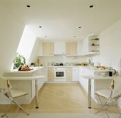 In einer modernen Küche im Dachgeschoss stehen jeweils links und rechts davon Frühstück Bars und Metall-Holzstühle mit weißen Sitzpolstern