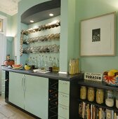 In einer lindgrünen und modernen Küche wurde eine Beleuchtung über den Edelstahl-Regalen mit Glas-Vorratsdosen angebracht