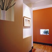 Ein Flur mit einer weißen, braunen und orangen Wand und einen Parkettboden