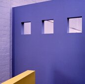 Eine violette Wand und ein gelbes Geländer