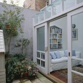 Ein moderner Wintergarten mit offenen Glasschiebetüren, die in den kleinen Innenhof führen