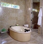 Badezimmer mit ovaler, freistehender Badewanne und mit beigen Mosaikkacheln