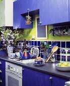 Moderne Küche mit blau lackierter Schrankfront und grünem Wandstreifen über blauen Wandfliesen
