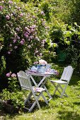Teepause im Garten mit weißem Tisch und Stühlen