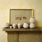 Rustikale Töpfe und Amphoren aus Keramik vor Bild auf Kaminsims