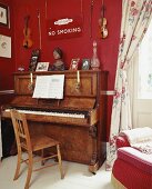 Antikes Klavier vor roter Wohnzimmerwand