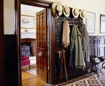 A traditional hallway with a collection of hats on the hooks next to the open living room door
