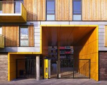 Modernes Wohnhaus mit Holzschiebeelementen neben Fenster und gelb vertäfelte Hauseinfahrt