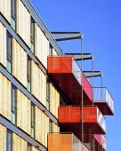 Modernes Wohnhaus mit farbigen Balkonen und Holzschiebeelementen