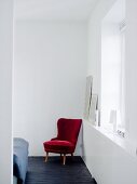 A red chair in the corner of a room