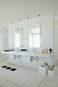 Ein Waschtisch mit zwei Waschbecken und Spiegeln an einer Trennwand in einem eleganten Badezimmer