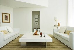 Ein niedriger weisser Couchtisch und zwei weiße Sofas in einem Wohnzimmer