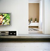 A flat screen television on the wall and multimedia devices in a sideboard
