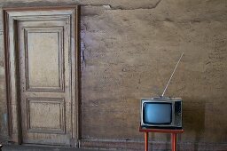 Television on a small table against a wall with a door