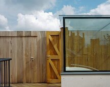 Modern glass staircase on a roof terrace and simple wooden wall with door
