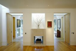 A minimalistic anteroom with a fireplace that also serves the living room and open doorways